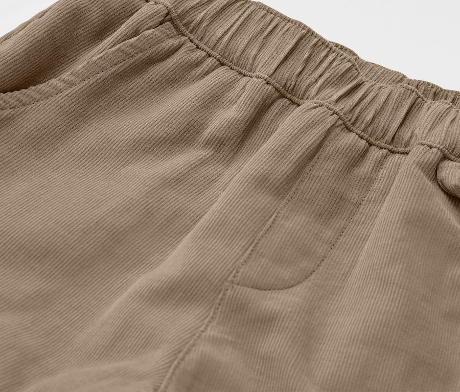 Detail detských menčestrových turistických nohavíc v hnedej farbe, ukazujúci elastický pás a vrecko.