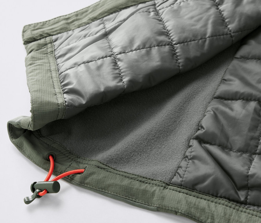 Detail prešívanej vesty »pack light« olivovej farby s oranžovou sťahovacou šnúrkou.