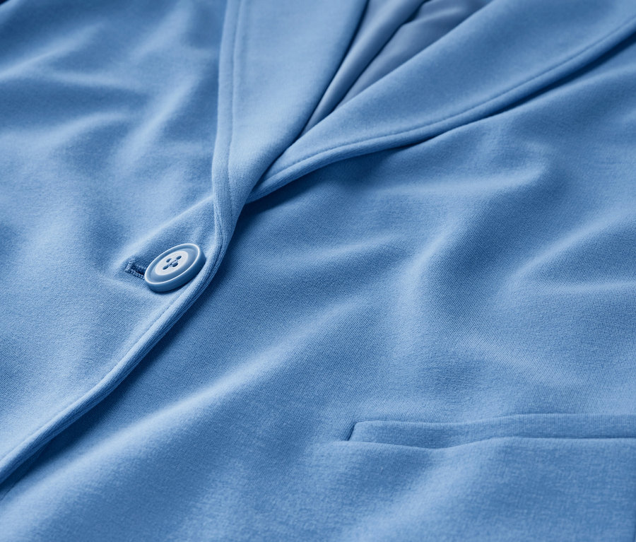 Detail svetlomodrého džersejového blejzra s gombíkom a vreckom.