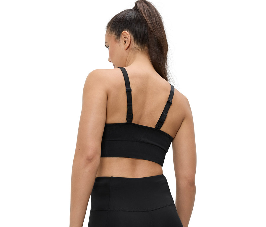Pohľad zozadu na ženu s copom, oblečenú v čiernej športovej podprsenke a legínach.