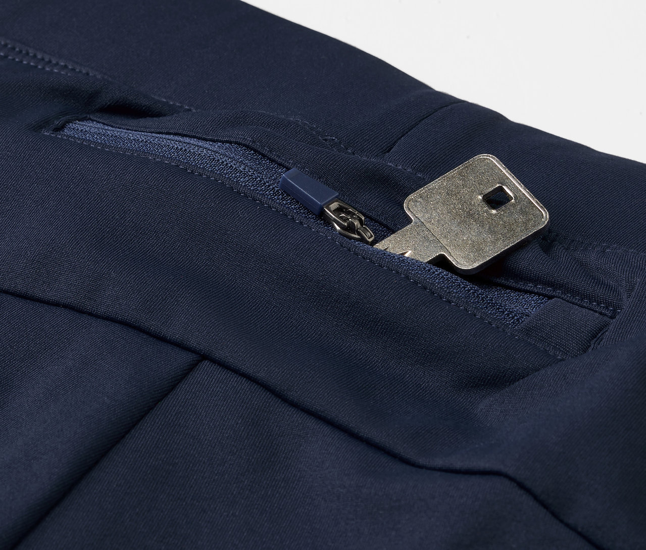 Detail modrých bežeckých legín Windprotection s kľúčom vo vrecku na zips.