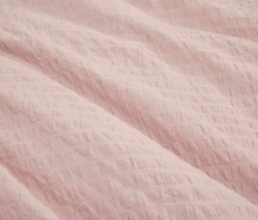 Detailný záber na textúrovanú svetloružovú látku.