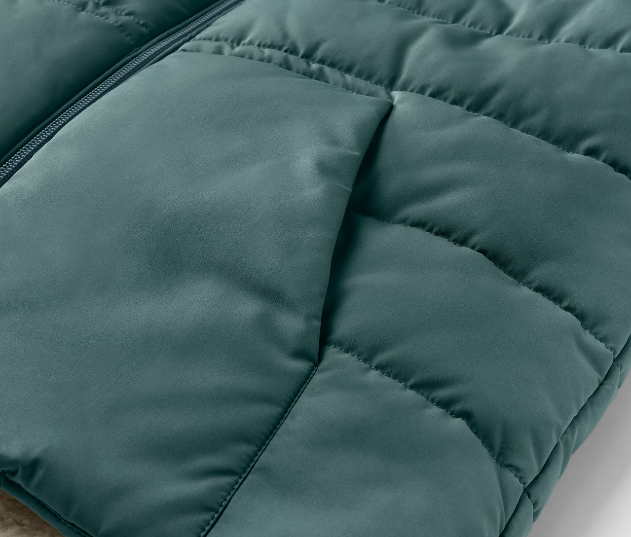 Detail detskej prešívanej vesty s plyšovou podšívkou a vreckom.