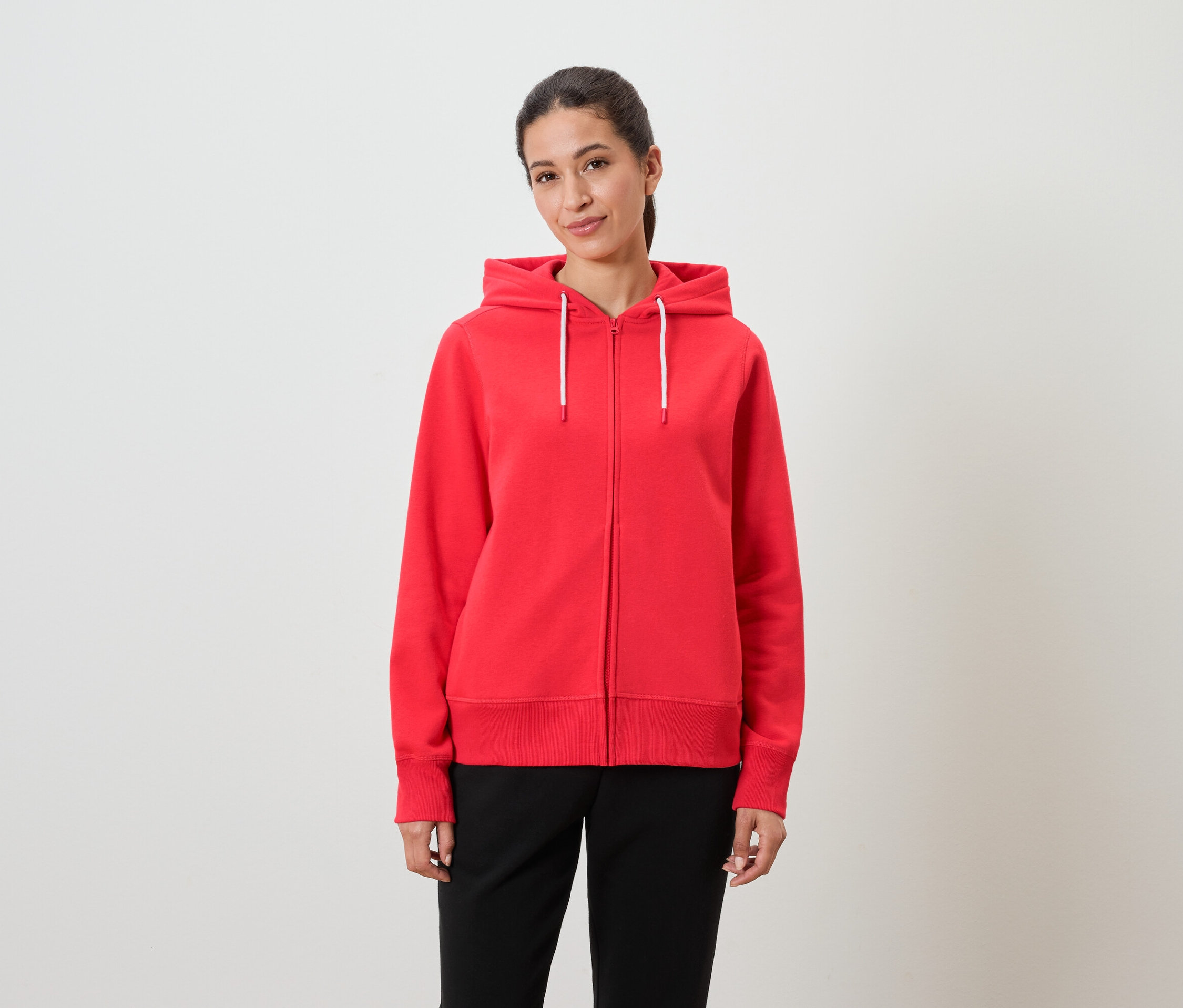 Žena má na sebe červenú mikinu s kapucňou a čierne nohavice.