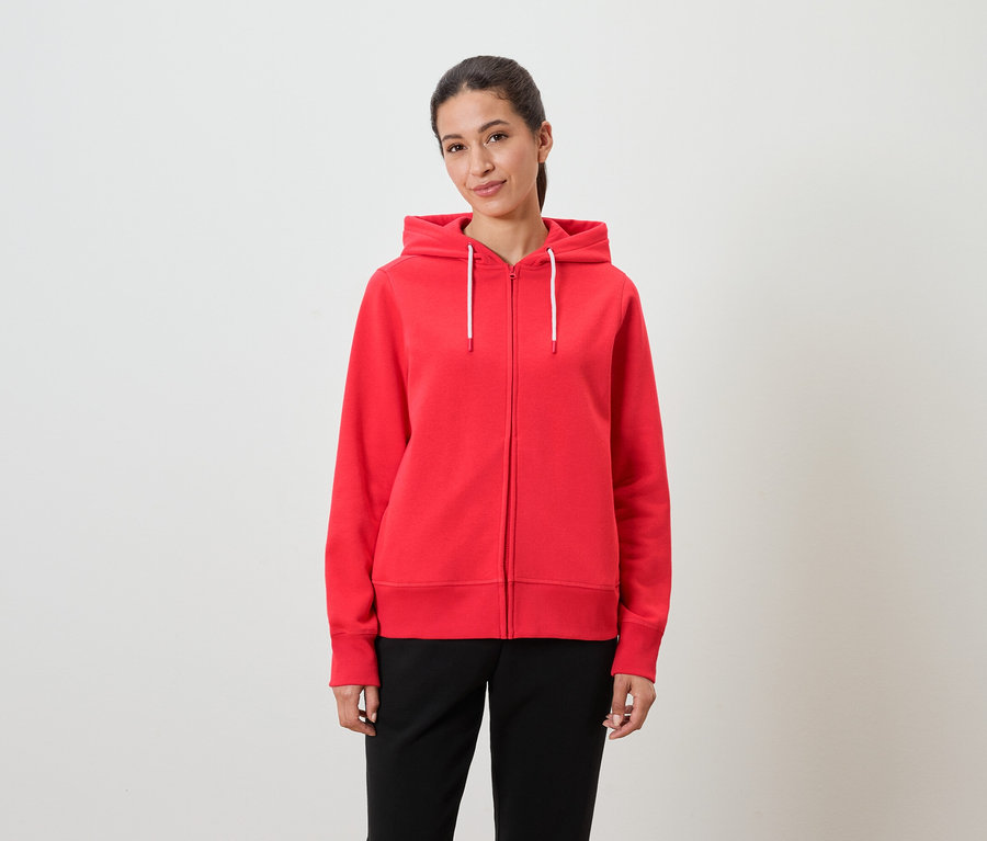 Žena má na sebe červenú mikinu s kapucňou a čierne nohavice.