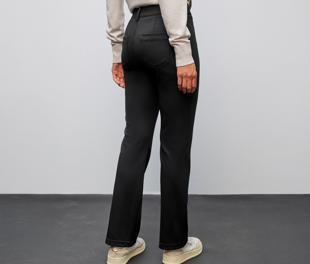 Osoba zozadu, oblečená v čiernych nohaviciach Street One Bootcut a svetlej obuvi.