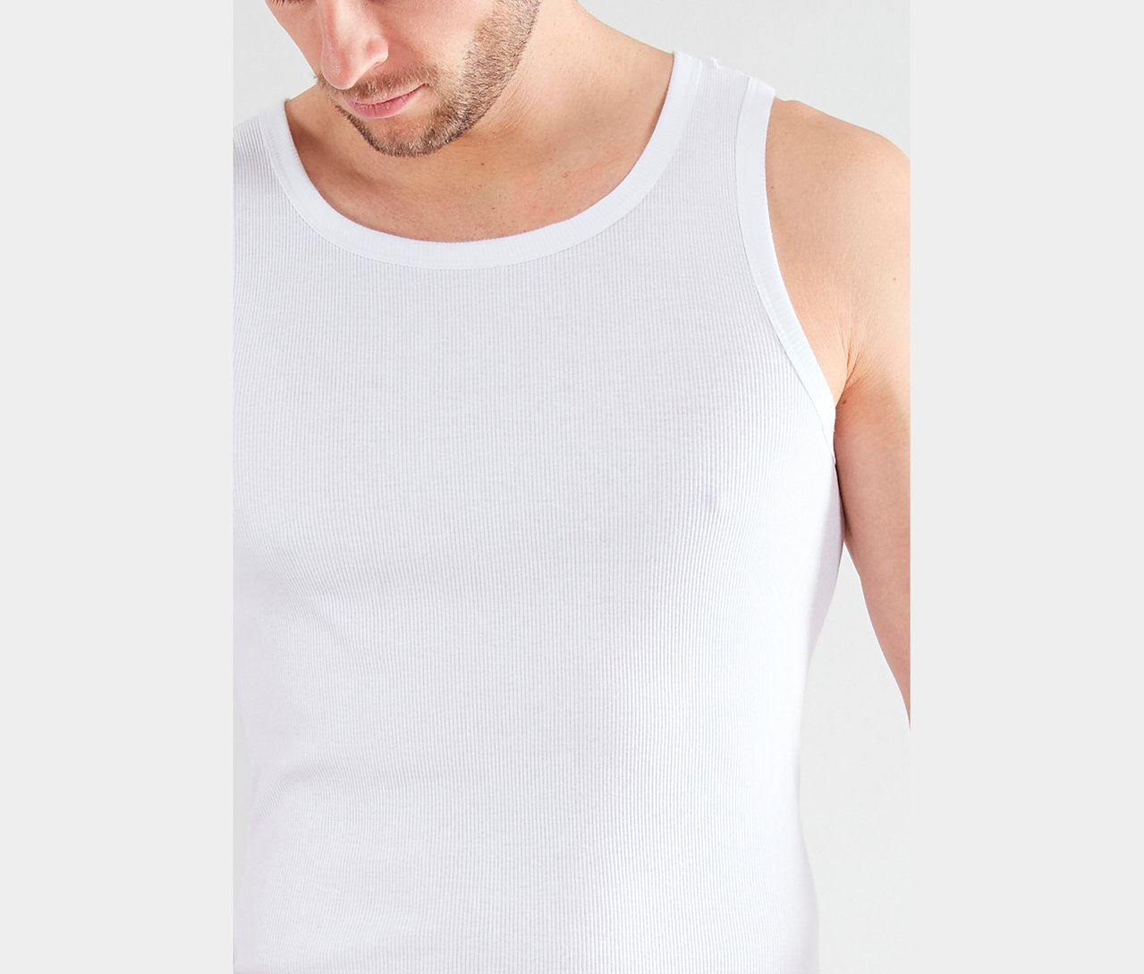 Detailný záber muža s bradou v bielom rebrovanom tielku.