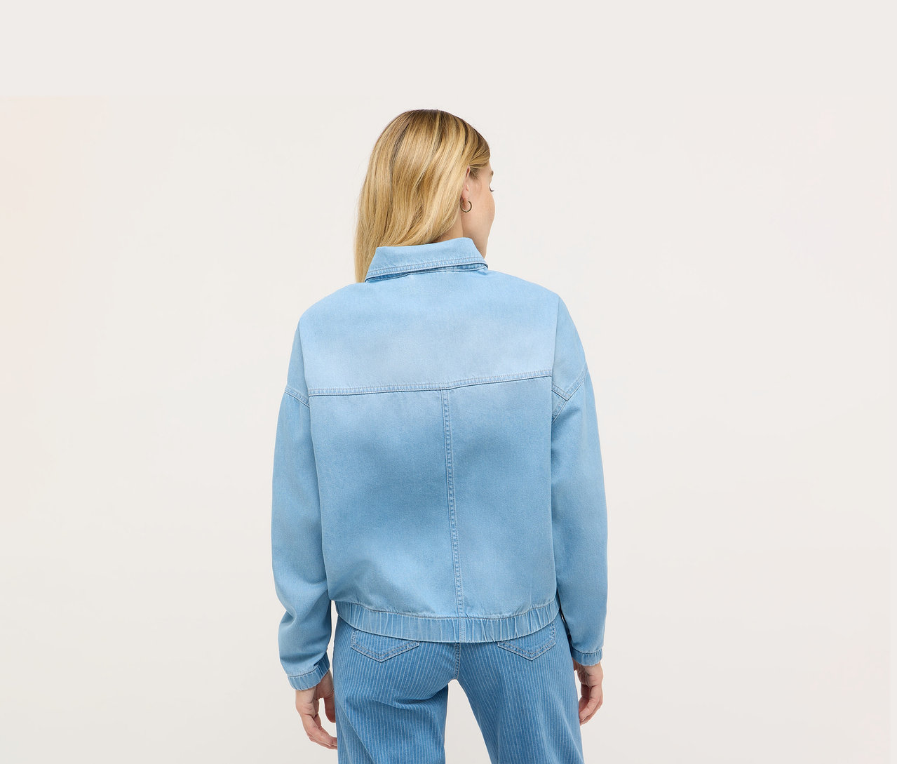 Pohľad zozadu na blondínku v modrej džínsovej bunde Angels.