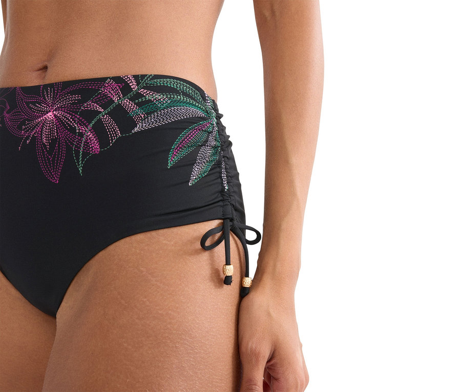 Detailný záber ženy v čiernych bikinových nohavičkách s kvetinovým vzorom.