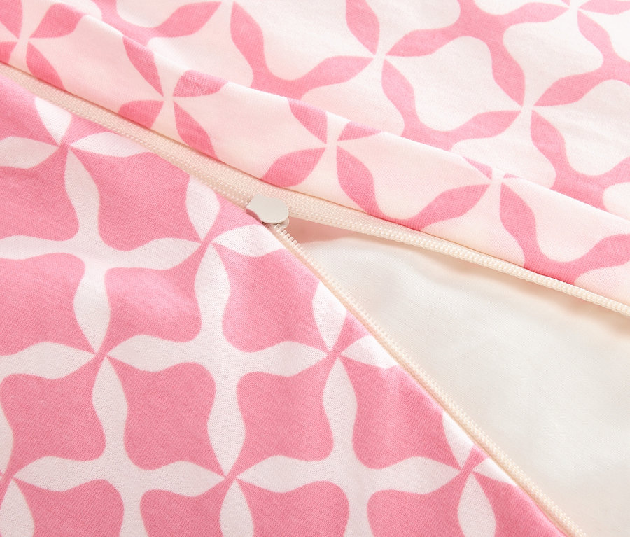 Detailný záber na čiastočne otvorený zips na ružovo-bielej vzorovanej látke.
