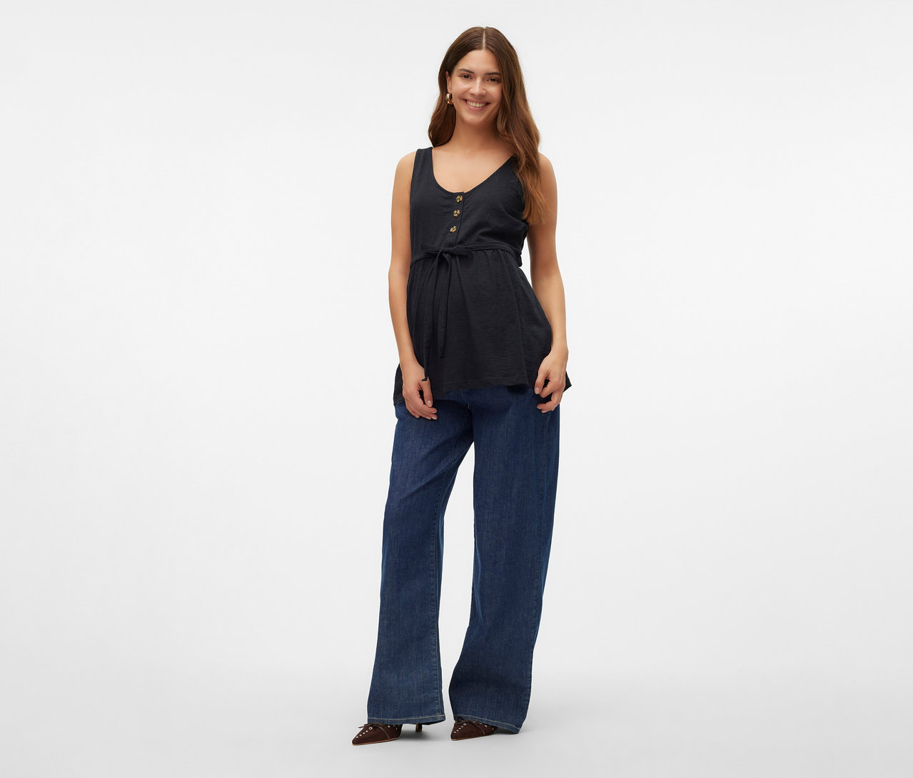 Žena má na sebe štýlový top MAMALICIOUS »MLEVI LIA«, džínsy a topánky.