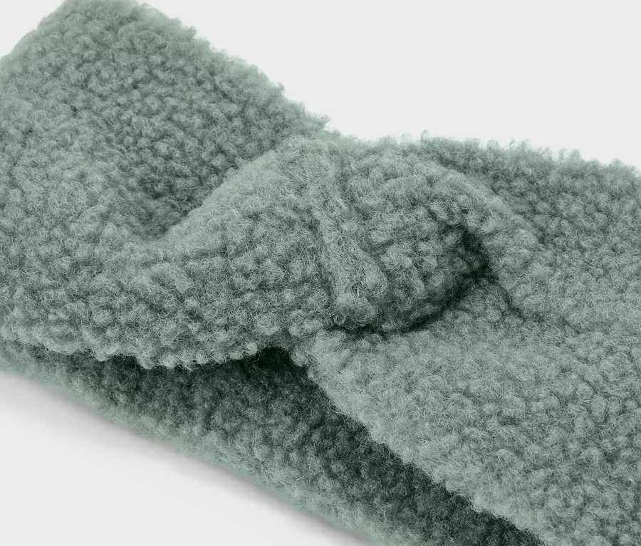 Detailný záber na svetlozelenú, skrútenú čelenku z plyšu teddy.