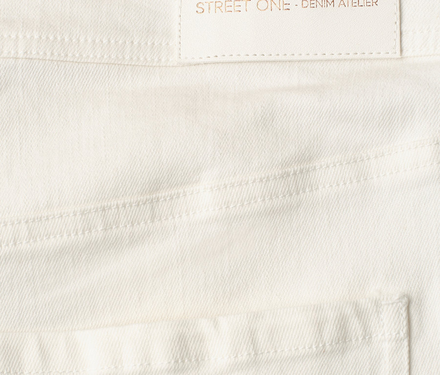 Detail bielych Street One Jeans s bledou etiketou s textom 'designed with passion STREET ONE - DENIM ATELIER'.