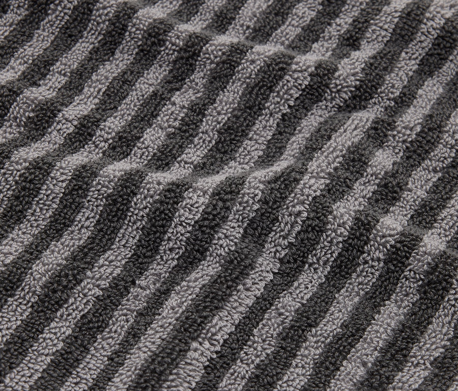 Detailný záber na pruhovaný uterák v odtieňoch sivej a čiernej.