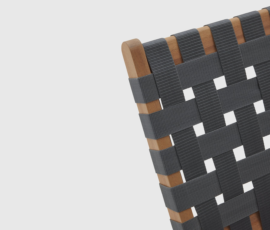 Detailný pohľad na stoličku s dreveným rámom a tkaným, sivým sedadlom.