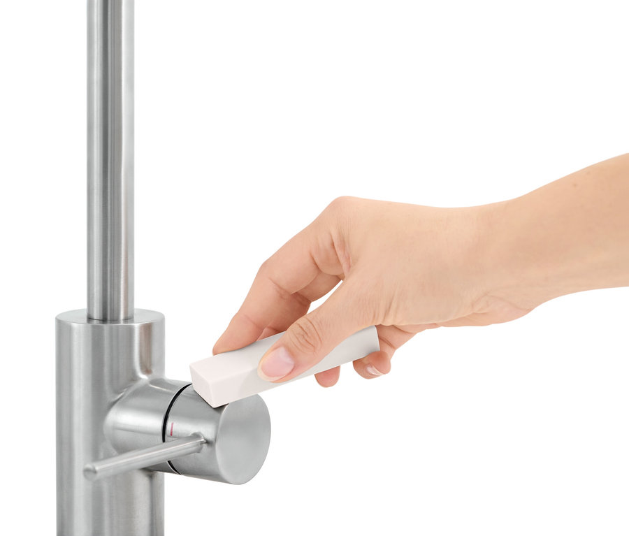 Ruka čistí vodovodný kohútik pomocou čistiacej hubky.