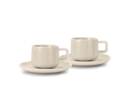 Dve béžové šálky na espresso s podšálkami, stojace vedľa seba.