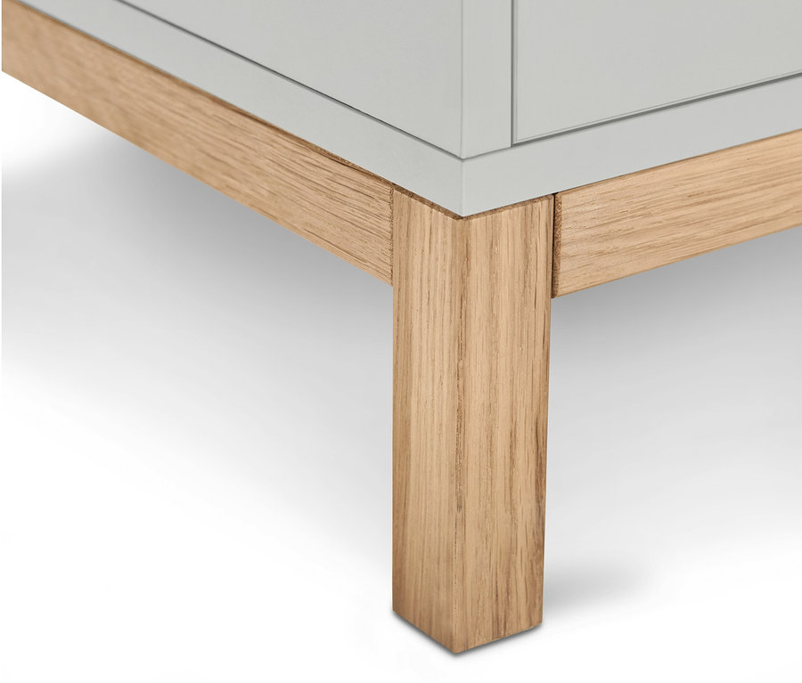 Detail spodnej časti svetlosivej skrinky pod umývadlo Eklund s dvomi zásuvkami a svetlými drevenými nohami.