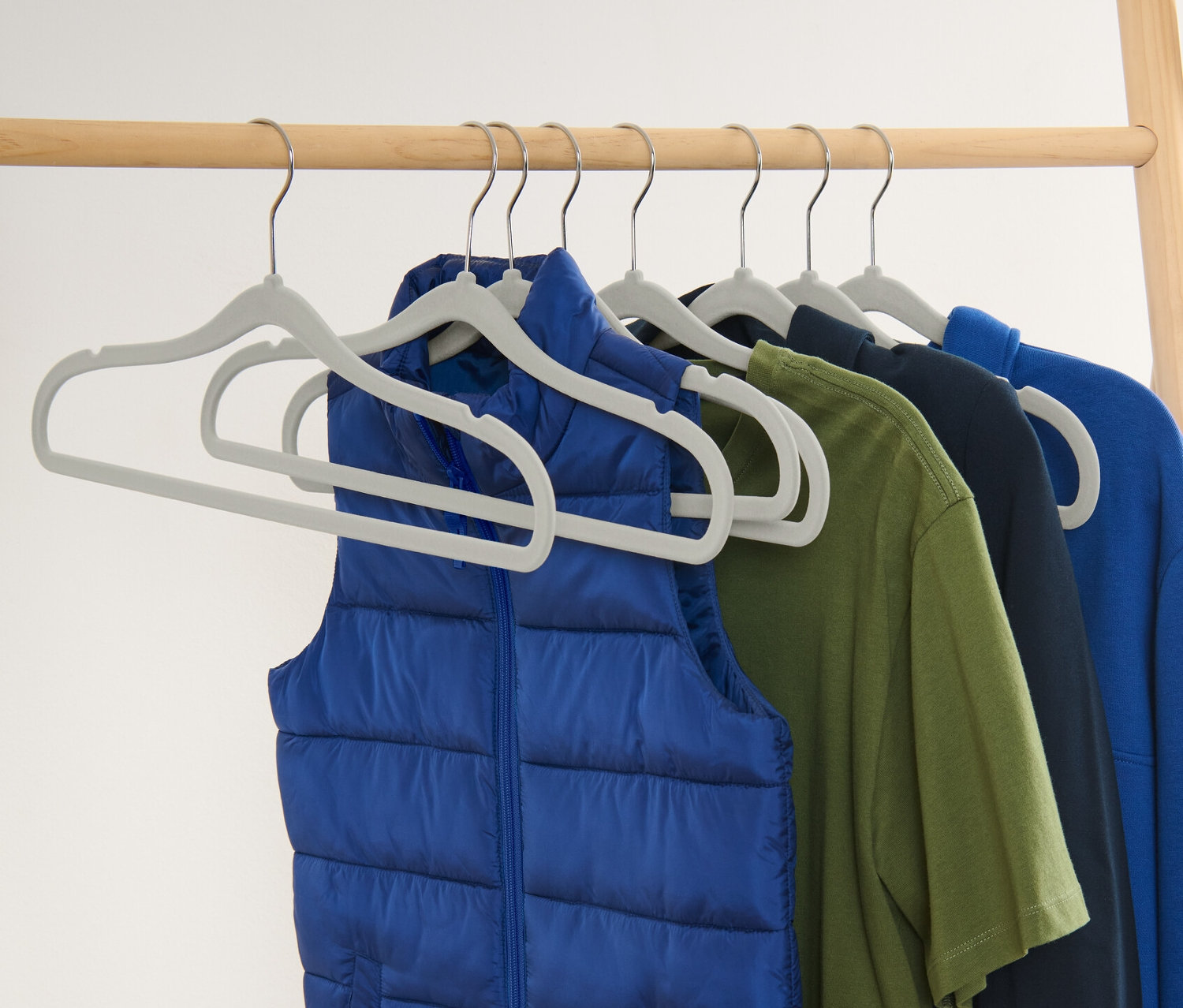 Modrá vesta a farebné oblečenie visia na ôsmich extra úzkych vešiakoch na šaty.