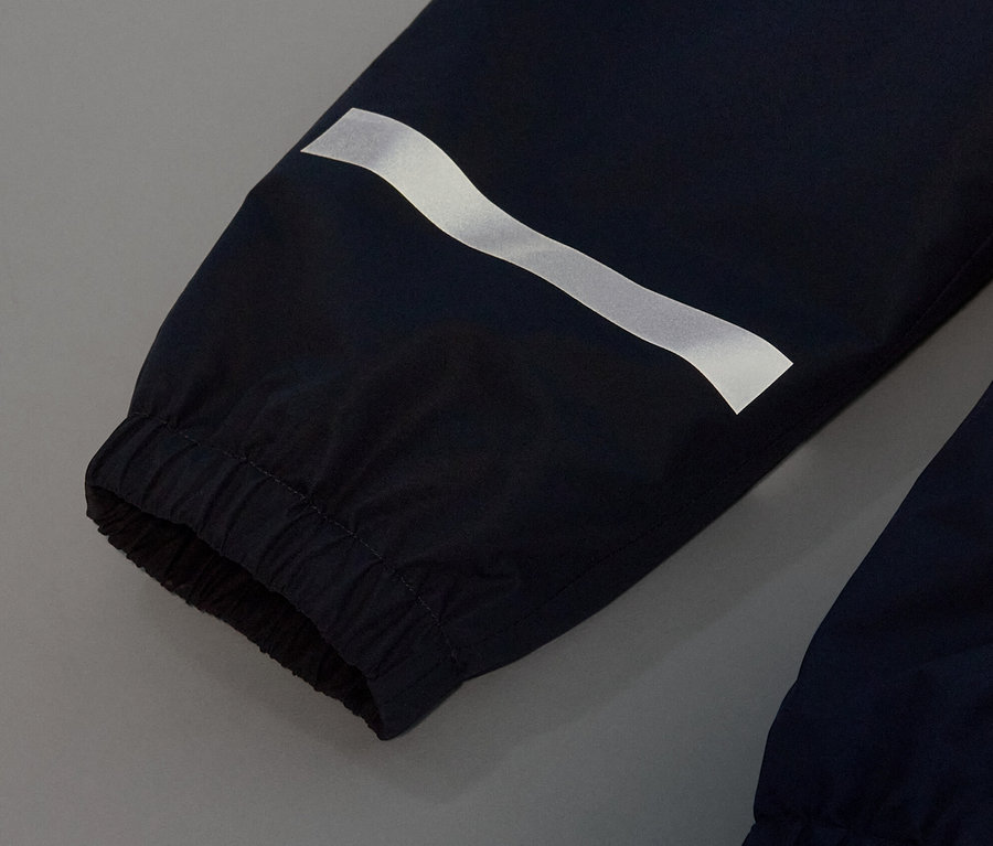 Detail detských nohavíc do dažďa tmavomodrej farby s reflexným pruhom.