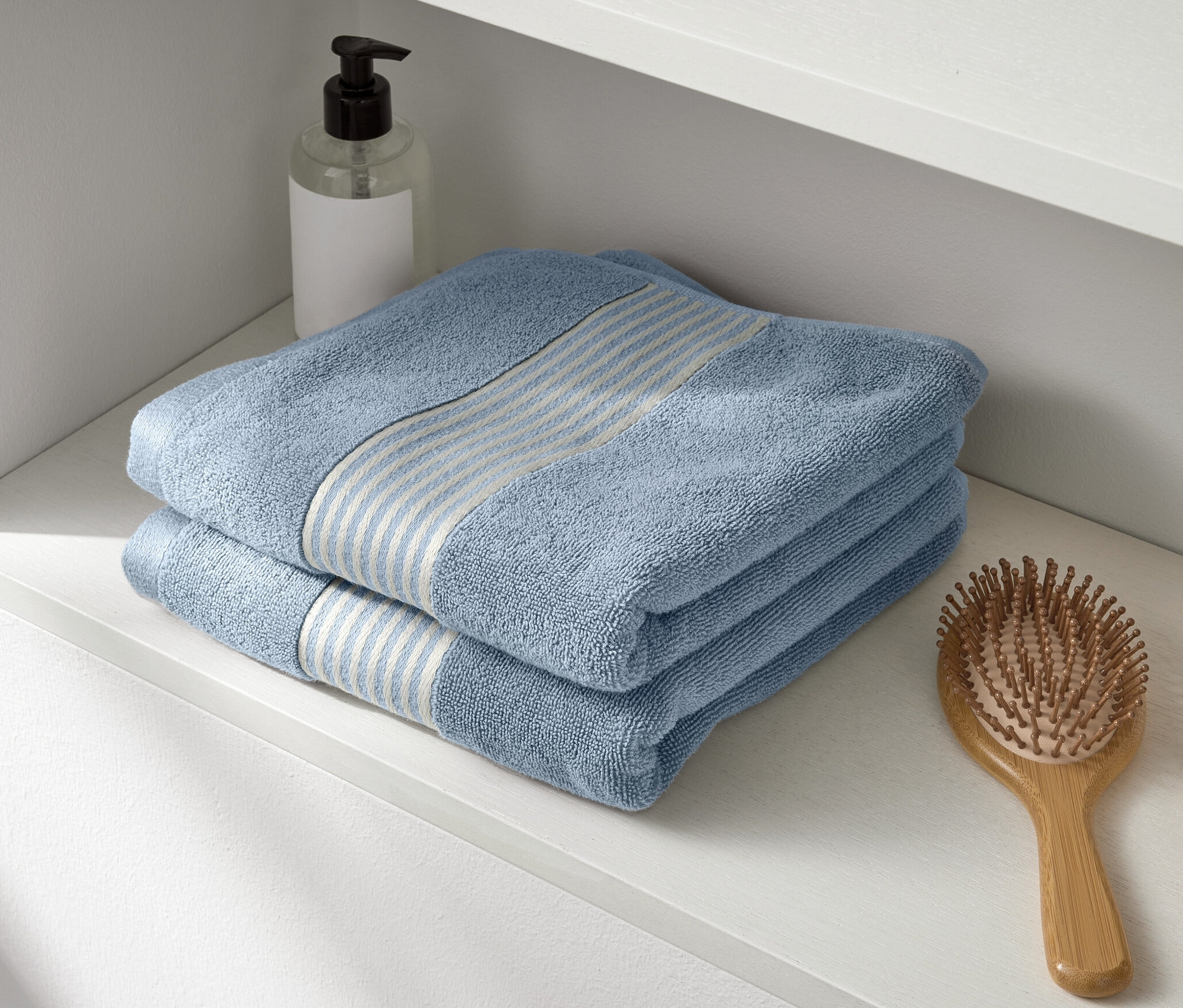 Na bielej poličke ležia dva modré prémiové uteráky.