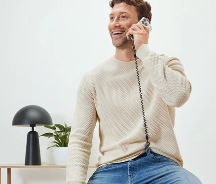 Muž sedí a telefonuje s bezpečnostnou retiazkou na mobil.