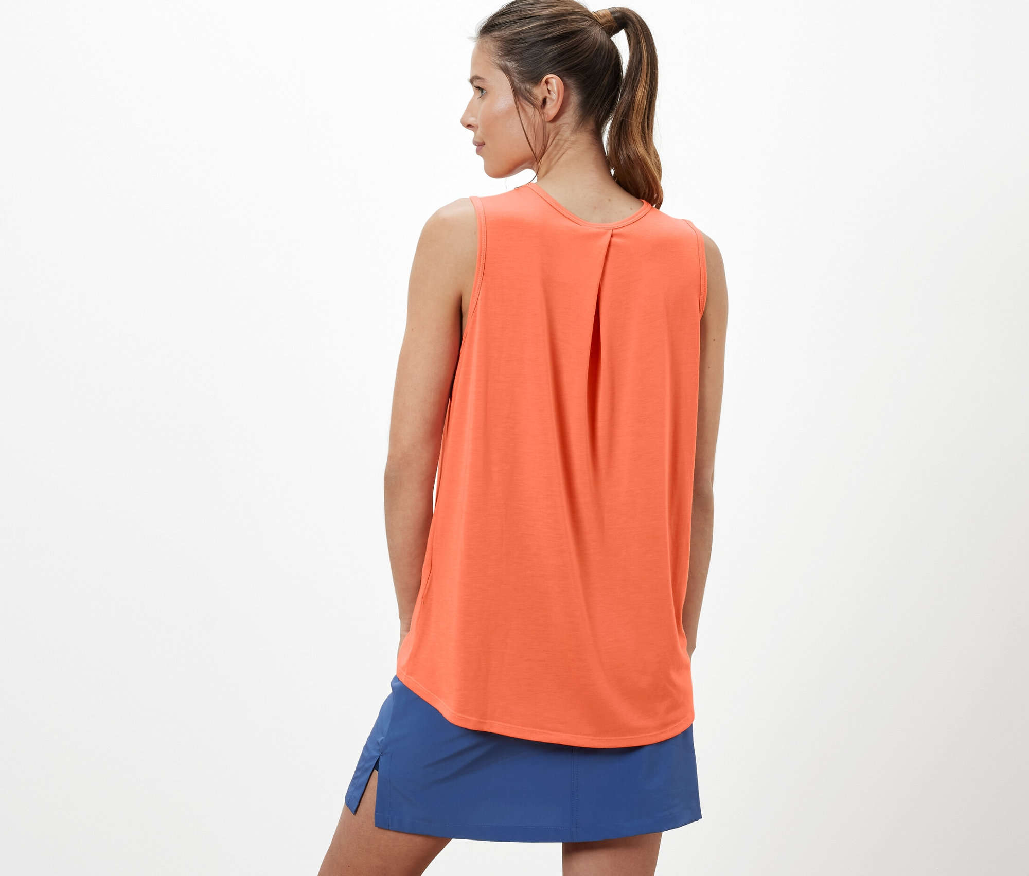 Žena má na sebe oranžový funkčný top a modrú sukňu.