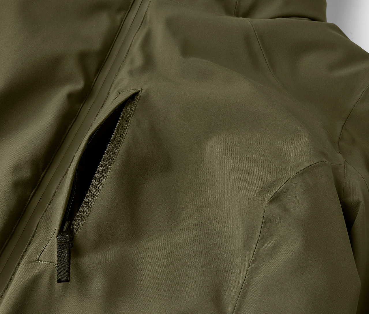 Detail olivovo zelenej bundy s vreckom na zips.