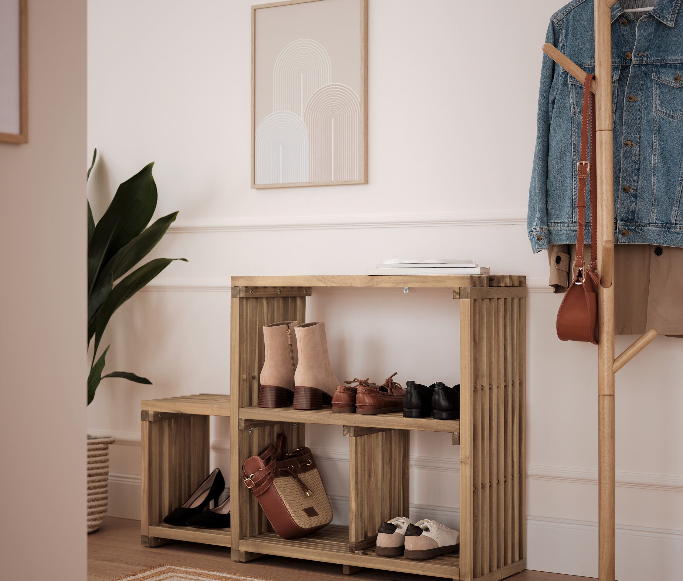 Bambusový botník s dvomi policami s topánkami a kabelkou, vedľa stojí vešiak na kabáty.