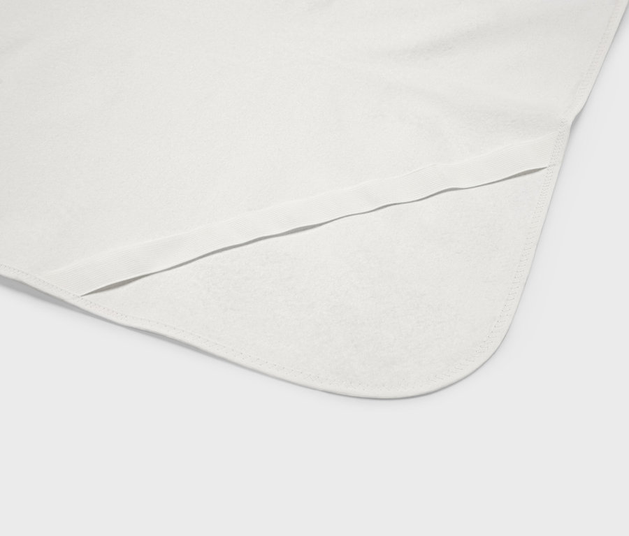 Detailný záber na bielu detskú deku so zaoblenými rohmi a elastickým lemom.