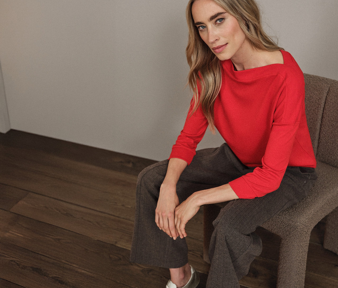 Žena sedí na stoličke a má na sebe červené tričko Street One s rebrovanými prvkami.