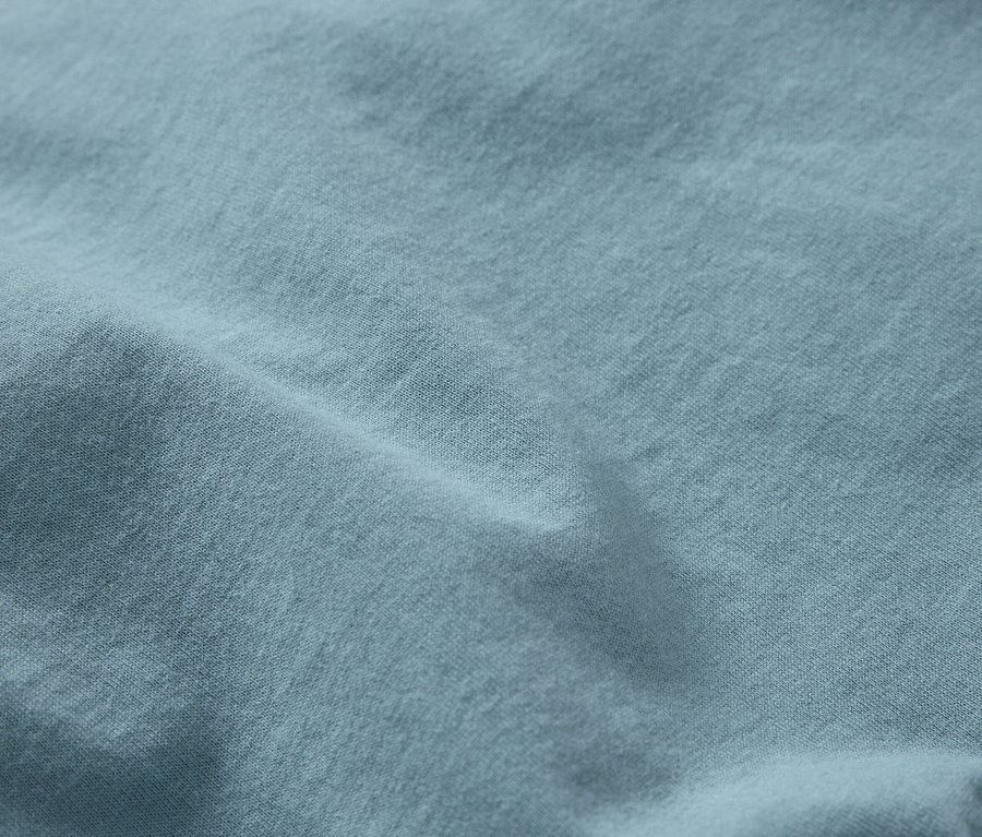 Detailný záber na svetlomodrú látku s jemnou textúrou a záhybmi.