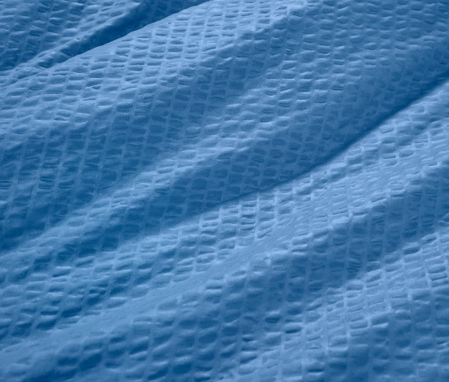 Detail modrej krepovej posteľnej bielizne.