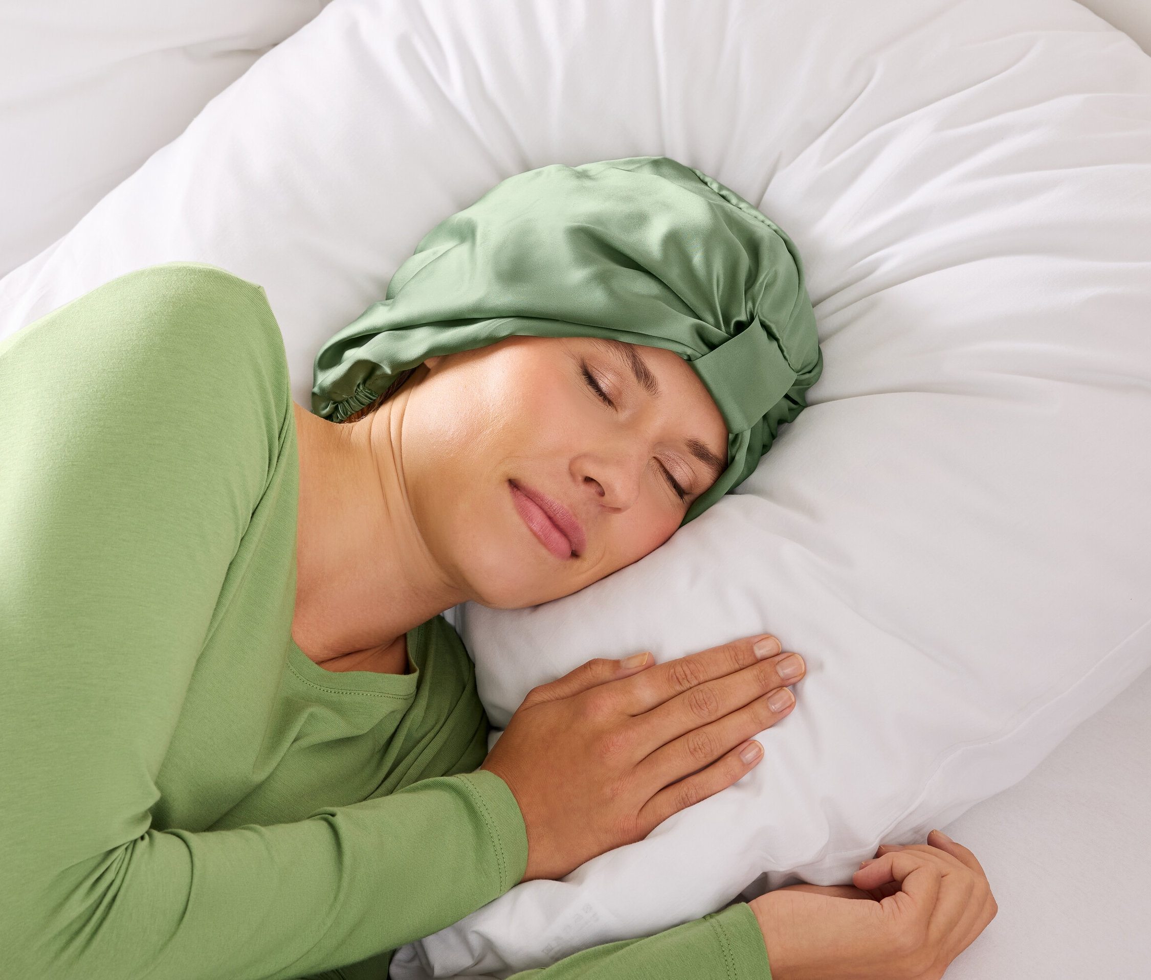 Žena spí so zelenou čelenkou na vlasy na bielom vankúši.