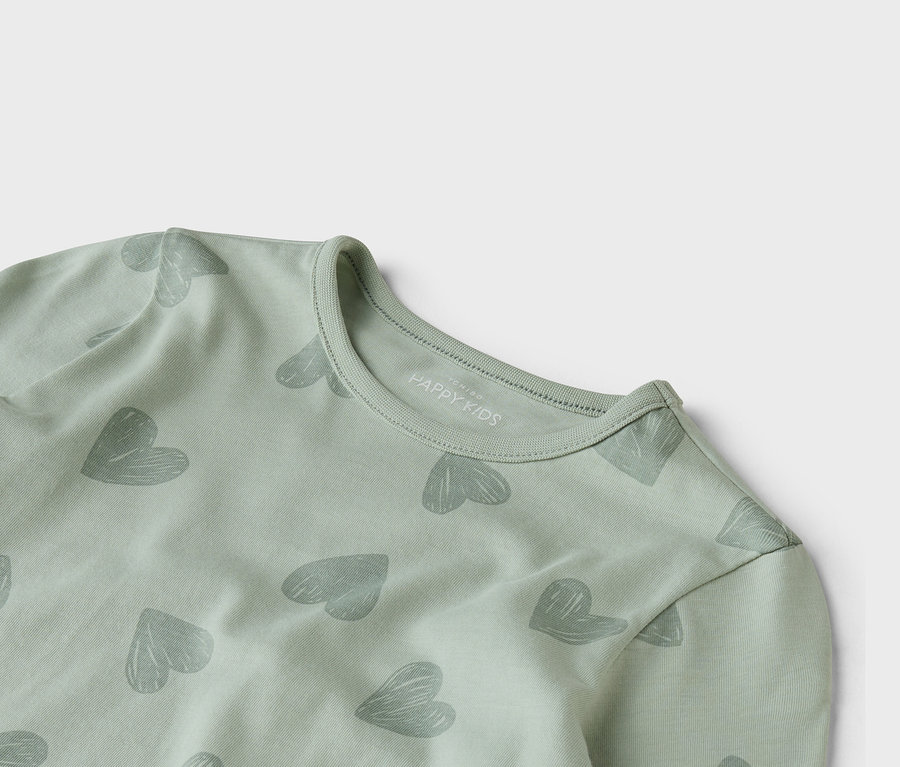 Detailný záber svetlozeleného trička s dlhým rukávom so sivým vzorom srdca.