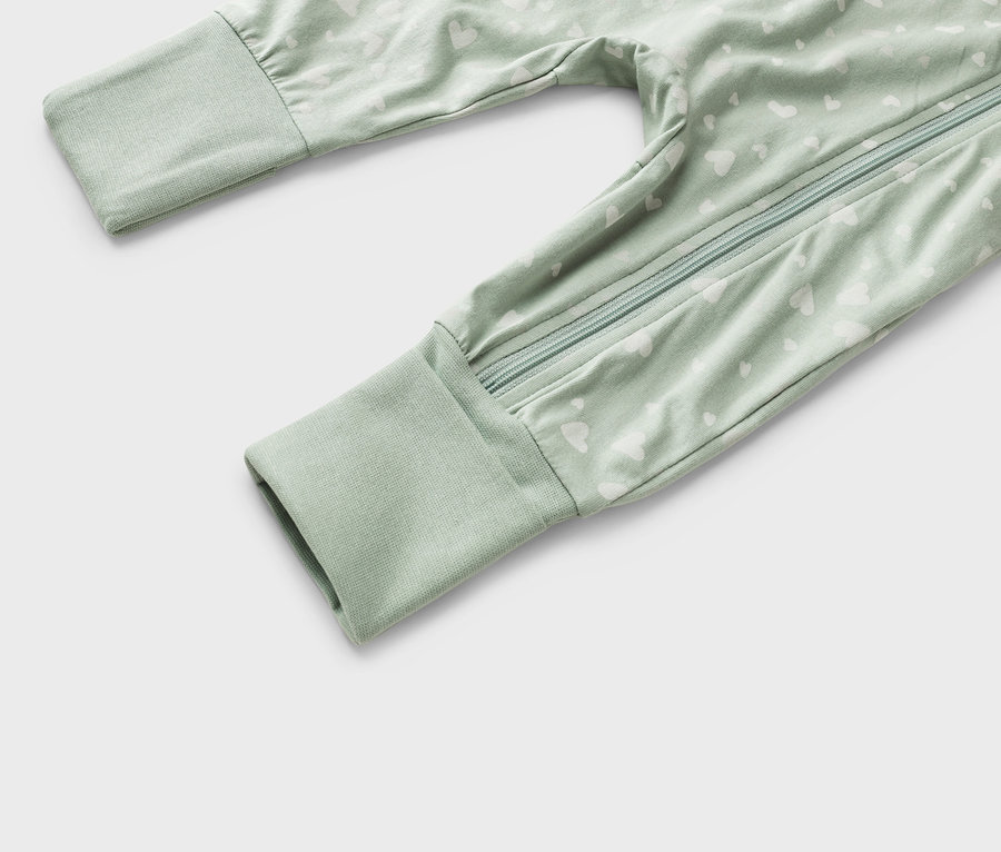 Detailný záber na svetlozelené detské pyžamo s bielym vzorom srdca a zipsom po celej dĺžke.