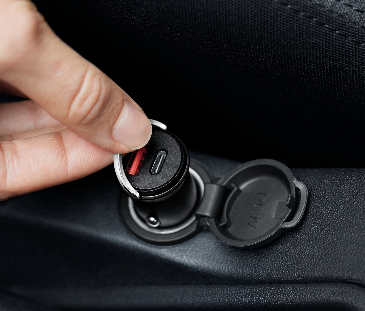 Ruka pripája čiernu nabíjačku do auta USB-C.