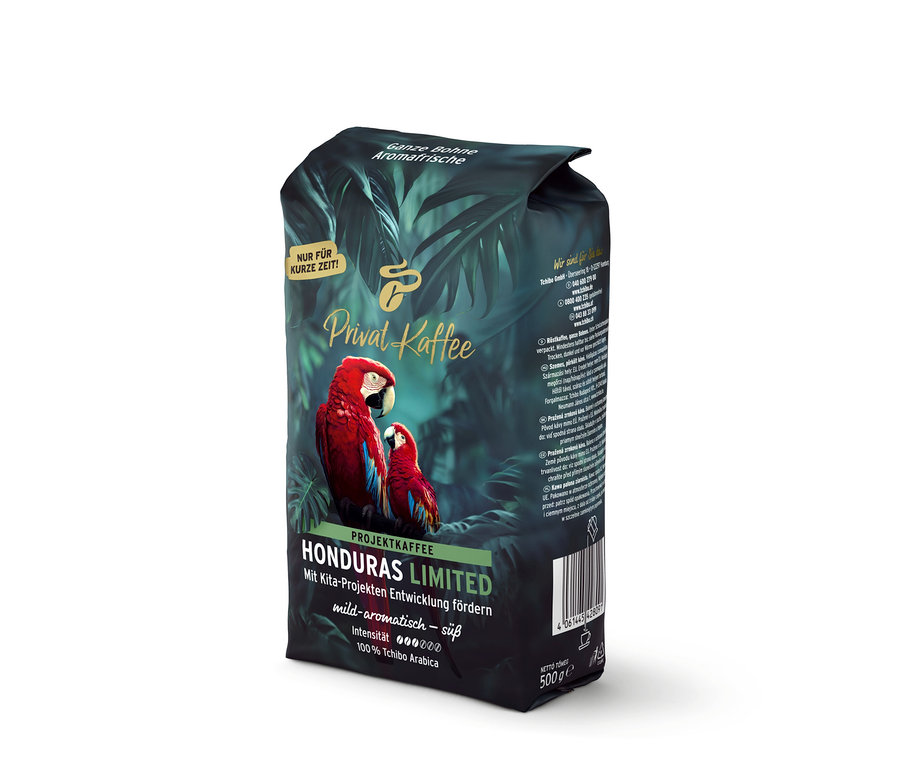 Tmavozelené balenie kávy Privat Kaffee Limited Edition Honduras s dvoma červenými arami a tropickými listami. Nápis: „Celé zrno, čerstvá aróma, jemne aromatická – sladká, 100% Tchibo Arabica“.