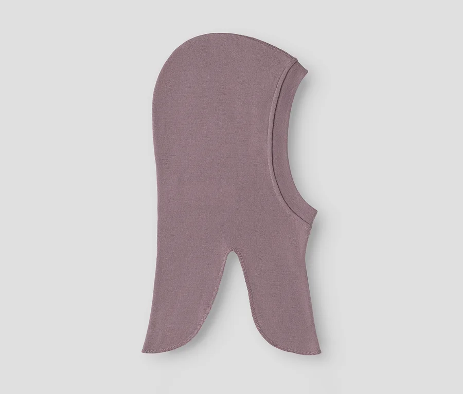 Kukla vo farbe mauve leží naplocho na sivom pozadí.
