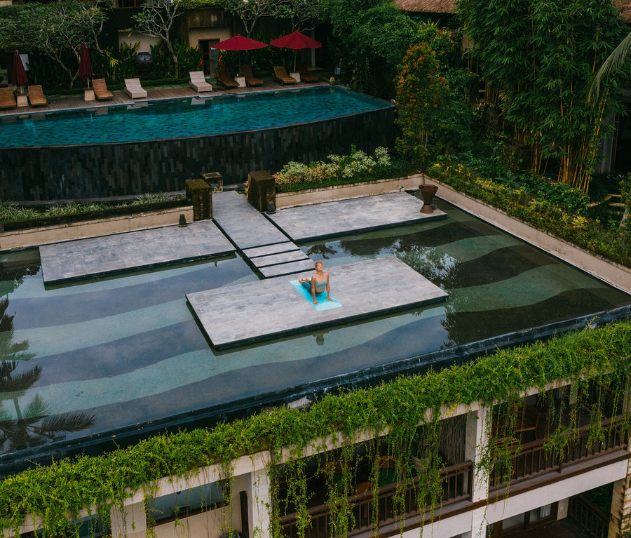 Žena cvičí jogu na plávajúcej plošine v bazéne.