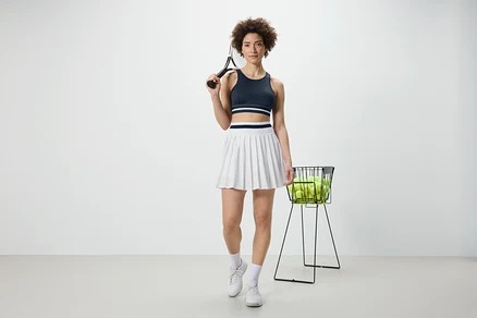 Žena drží tenisovú raketu a má na sebe modrú športovú podprsenku »Crop Top«.