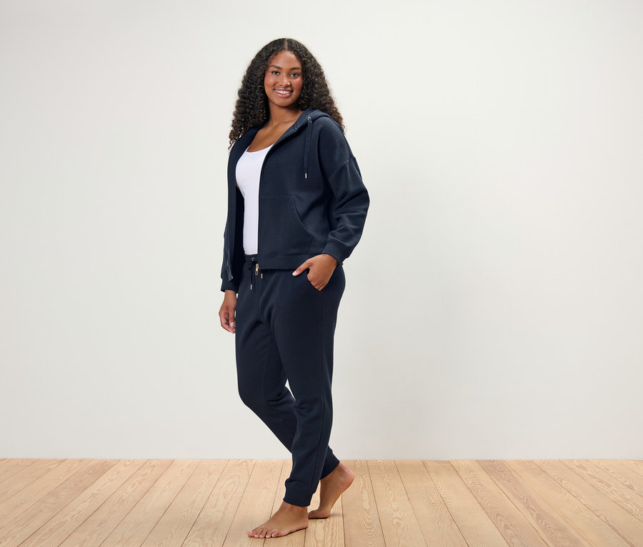 Žena stojí a pózuje v tmavomodrej domácej súprave.