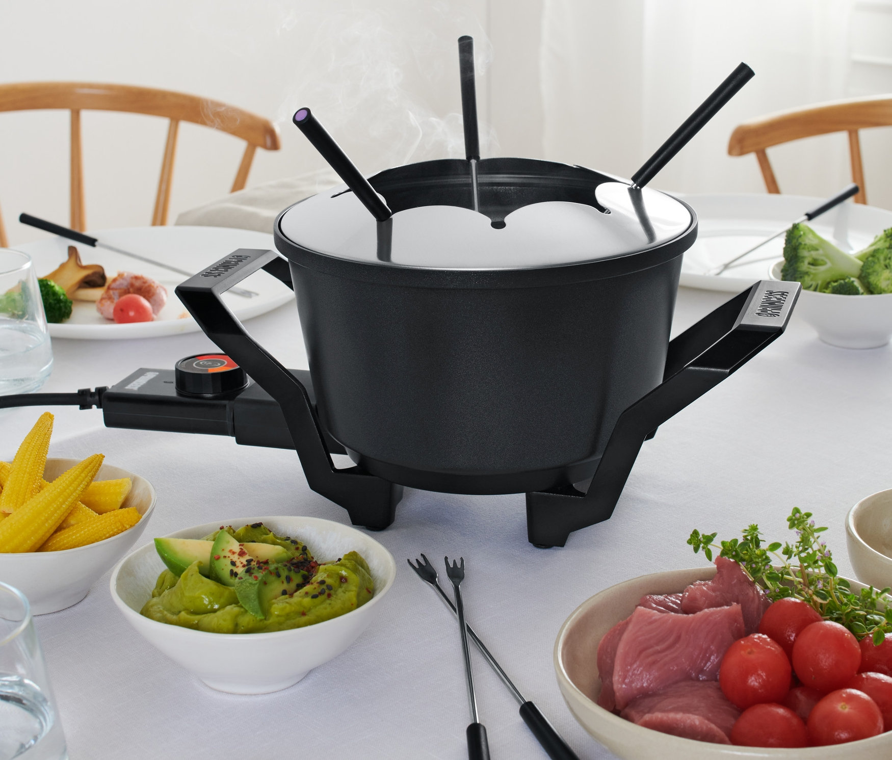 Na stole stojí fondue s napichovadlami a prísadami.