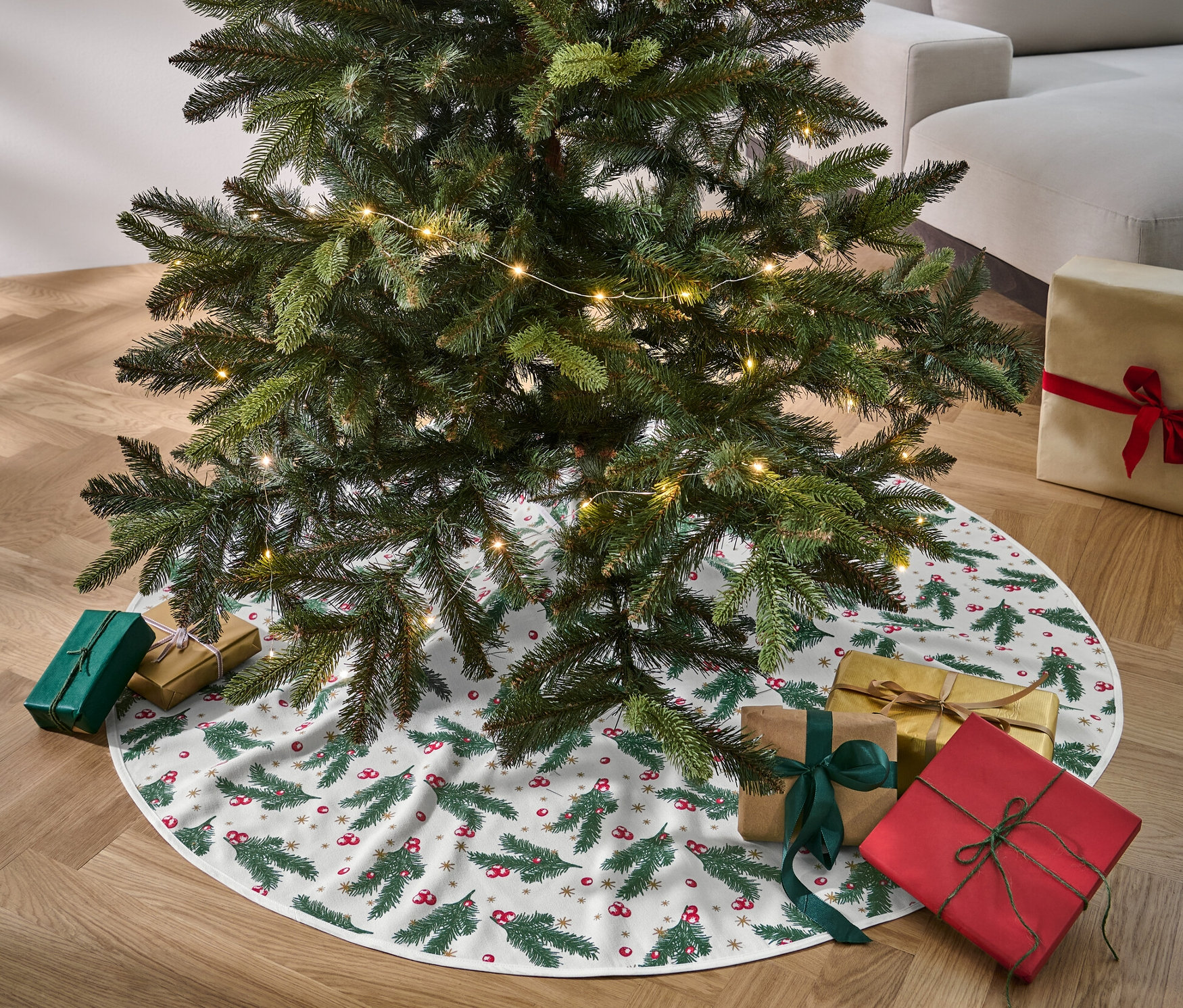Vianočný stromček stojí na deke pod vianočný stromček a okolo neho sú darčeky.