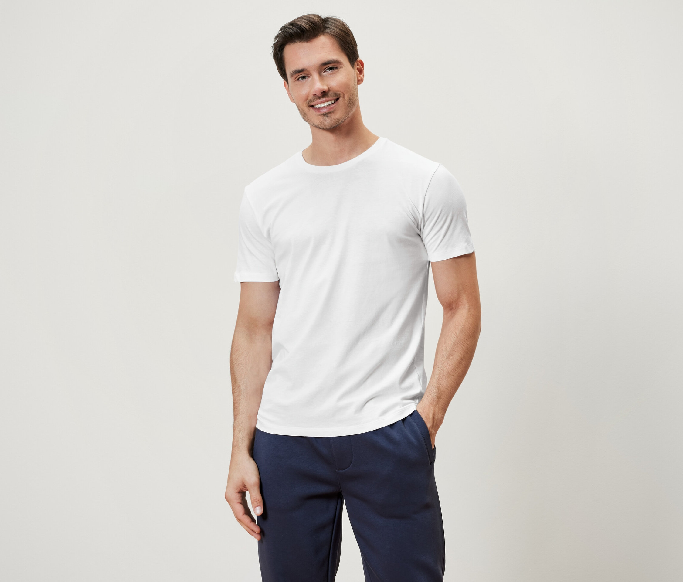 Muž pózuje v bielom tričku s okrúhlym výstrihom, ktoré je súčasťou sady 3 kusov.