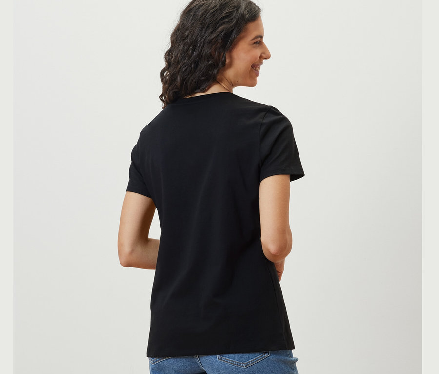 Žena sa pozerá cez plece a má na sebe čierne tričko Basic.