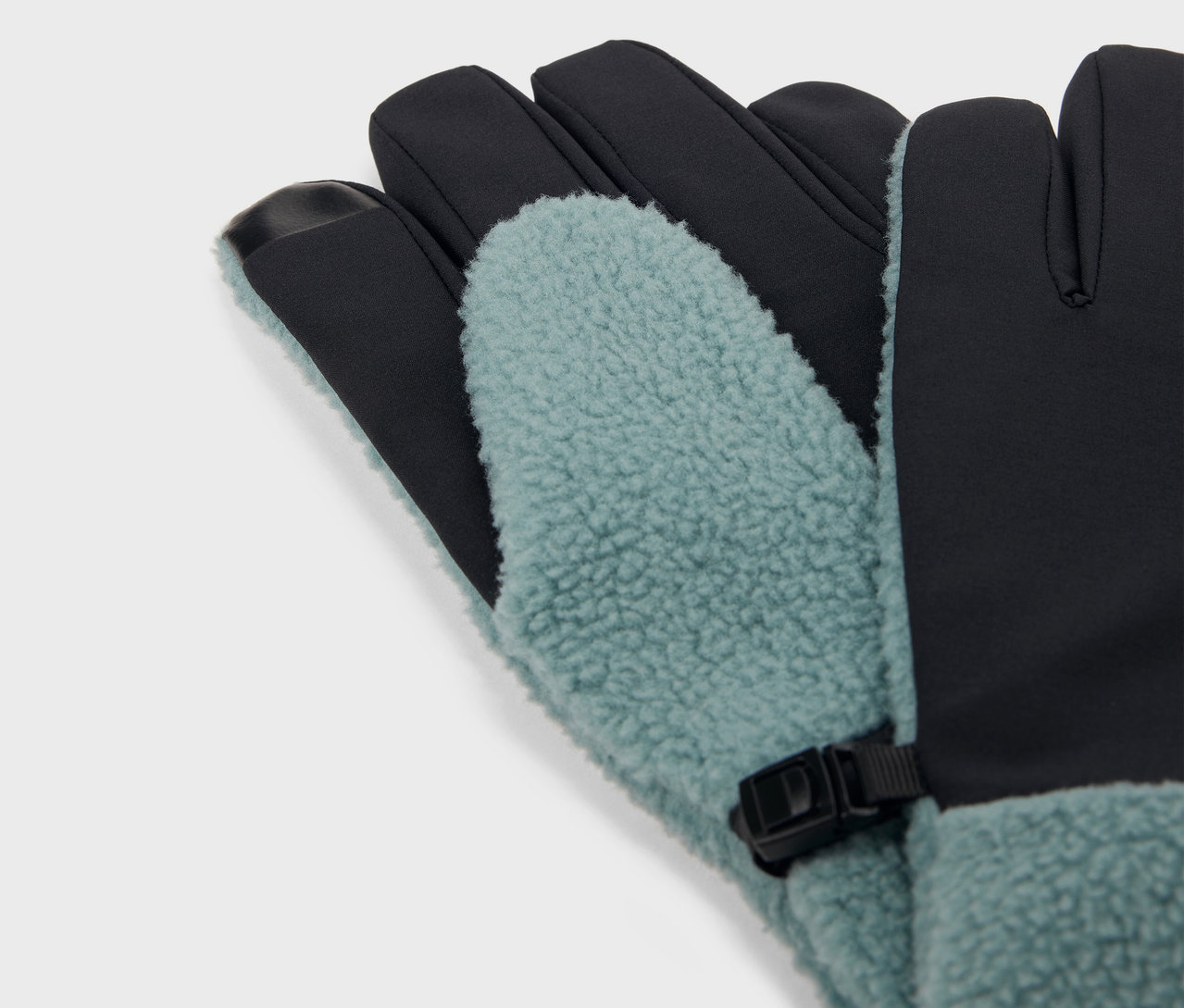 Detail modrých a čiernych rukavíc s flísovou podšívkou a čiernou sponou.