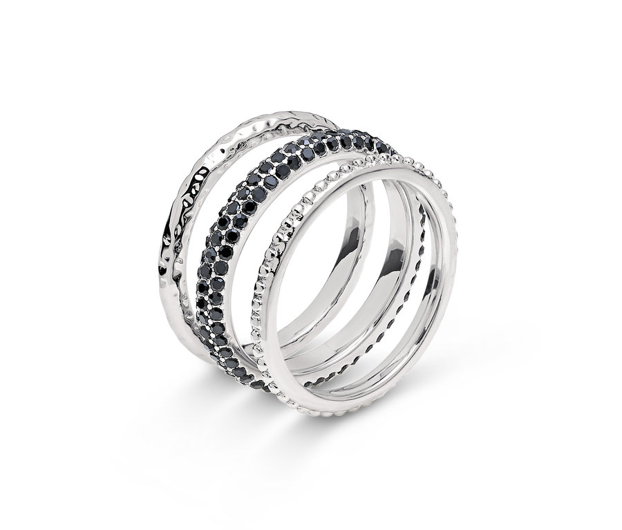 Detail strieborného prsteňa so štyrmi pásikmi, jeden s čiernymi kamienkami.