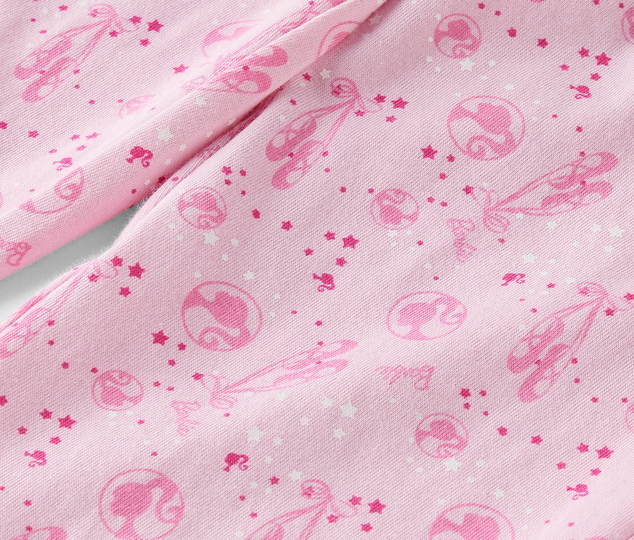 Detail ružovej látky s potlačou baletiek, hviezd a siluet Barbie.