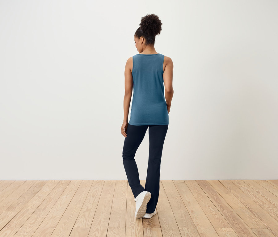 Žena chrbtom k fotoaparátu má na sebe modrý top a tmavomodré nohavice.